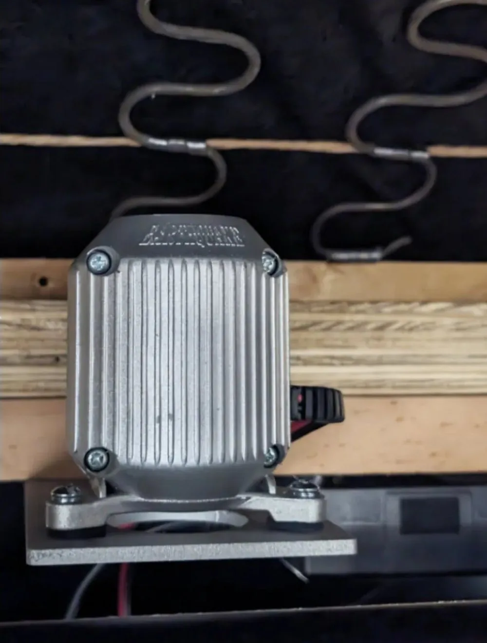 An Earthquake MQB-1 bass shaker bolted under the frame of a theatre seat