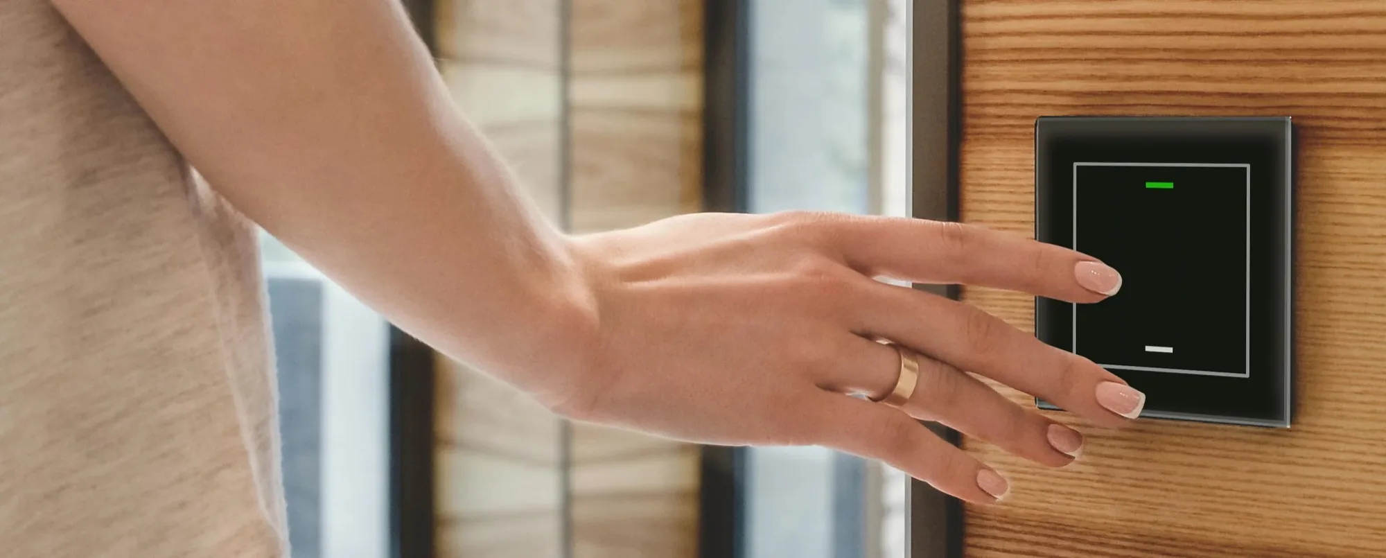 A hand reaching for a black MDT glass push-button on a wood-panelled wall