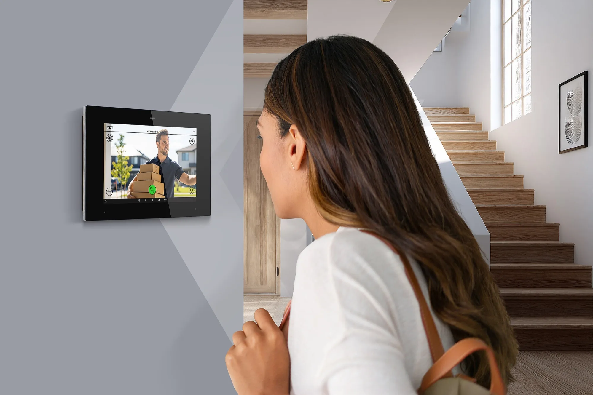 A woman looks at an MDT VisuControl Plus touch panel on a hallway wall