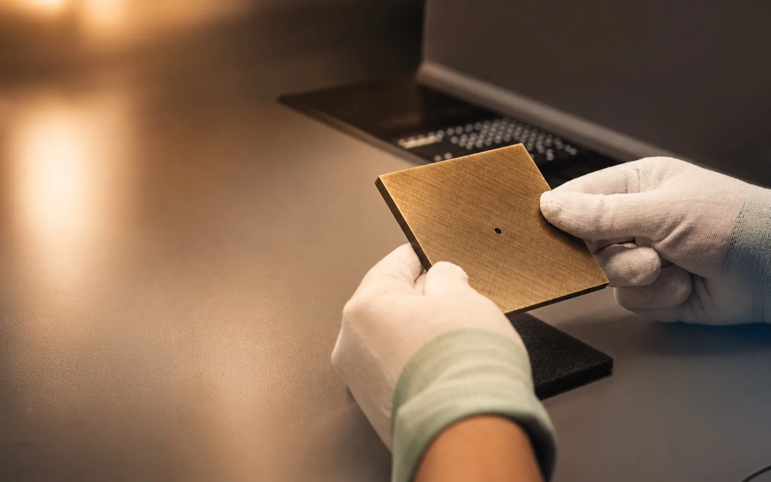 Gloved hands inspecting a bronze-coloured Tense front at a workbench
