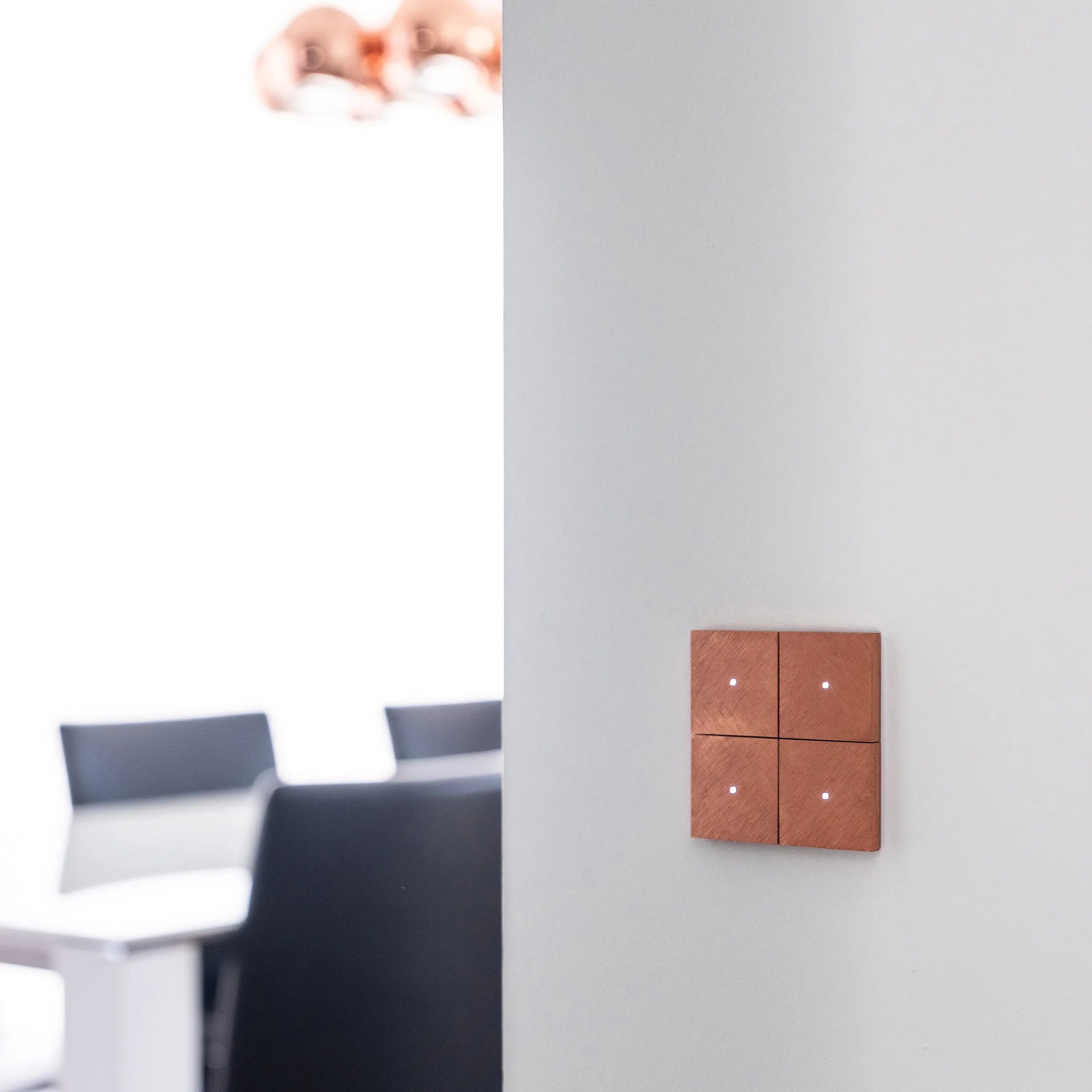 A copper-rose Tense Intensity push-button on a white wall