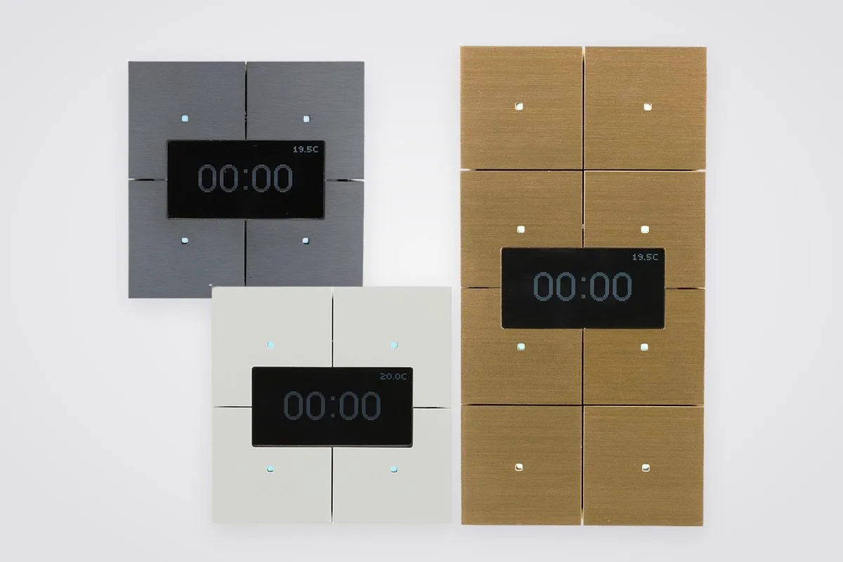 Three Infinity room controllers, each with a small display: a grey and a cream four-fold and a gold eight-fold